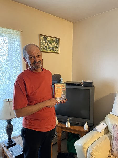photo of a man wearing a red T-shirt holding a DVD in front of a television set