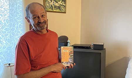 image of man in a red shirt holding a DVD in front of a television set