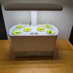 A hydroponic garden with a heat lamp on it growing a variety of herbs.