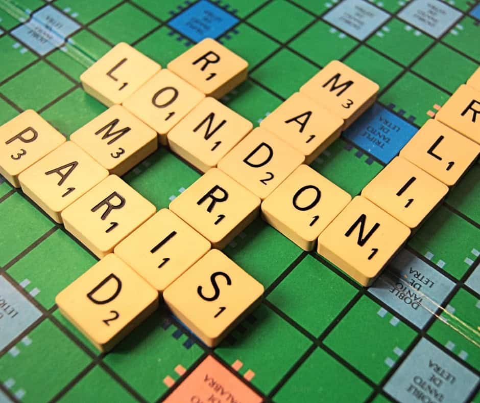 A green Scrabble board with city names spelled out on it.
