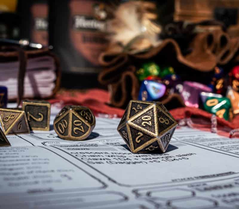 Dungeons and dragons dice are spilled onto a character sheet. A d20 is facing the camera.