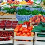 Various wooden boxes of fruits and vegetables on display at a farmers' market.