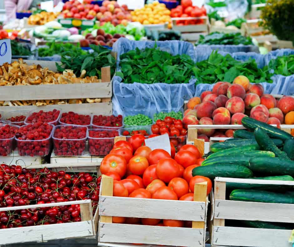 Various wooden boxes of fruits and vegetables on display at a farmers' market.