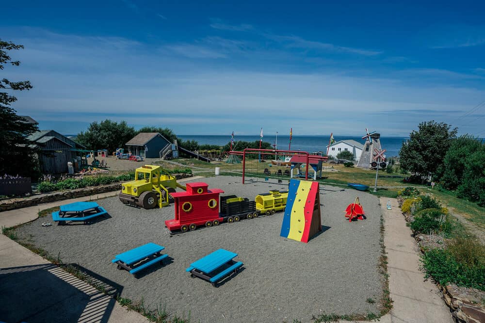 The Meteghan Family Park. The playground has a rock climbing wall, swings, and a wooden train and truck to play in.